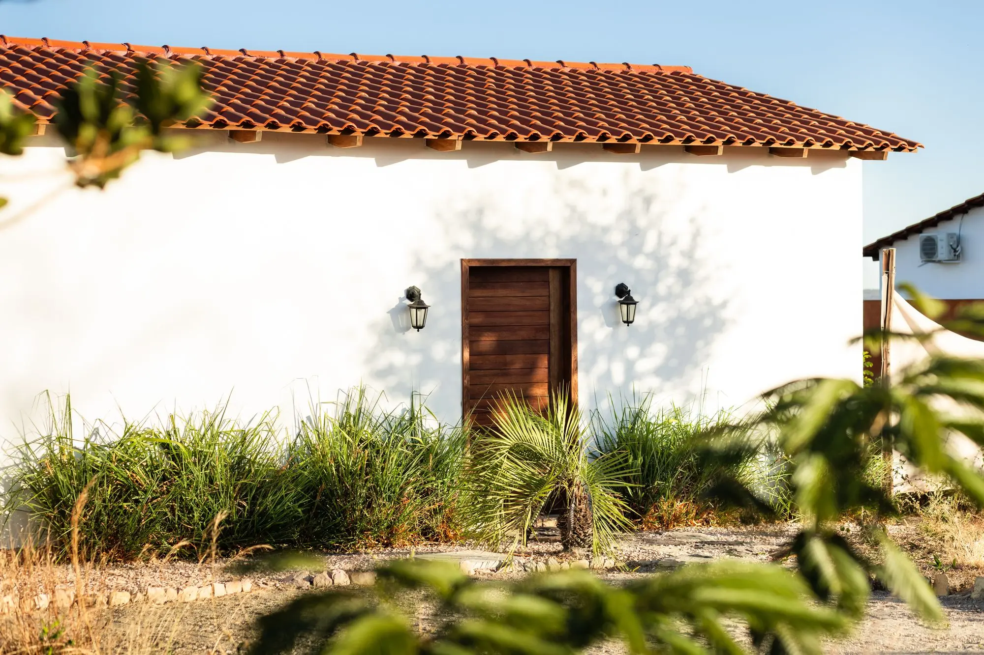 Entrada do Chalé Premium Duplo c/ Hidromassagem: porta de madeira, paredes brancas e telhado colonial