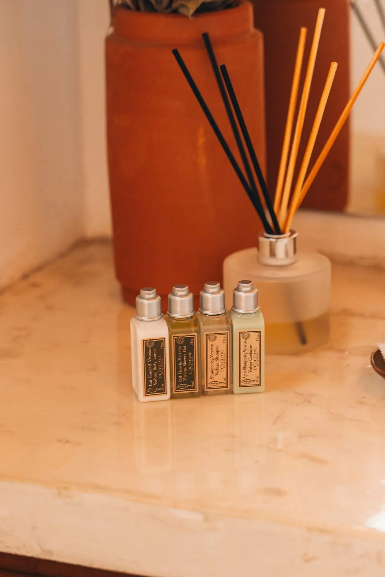 Amenities L'Occitane Verbena no banheiro do chalé com difusor de aromas e bancada de mármore