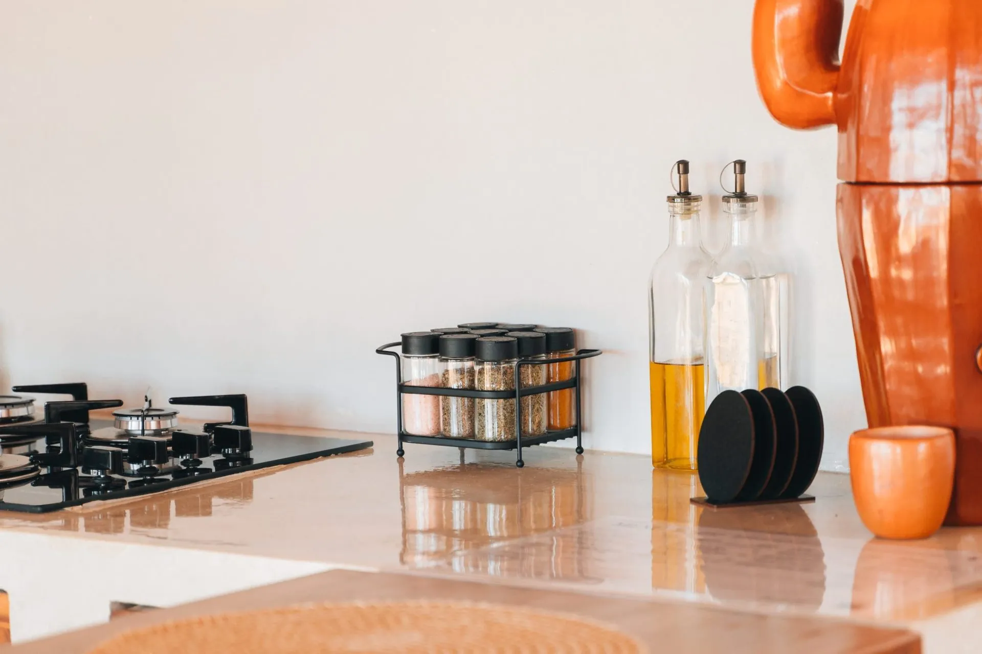 Detalhe da cozinha do chalé com fogão cooktop, porta-temperos, azeite e filtro de barro artesanal