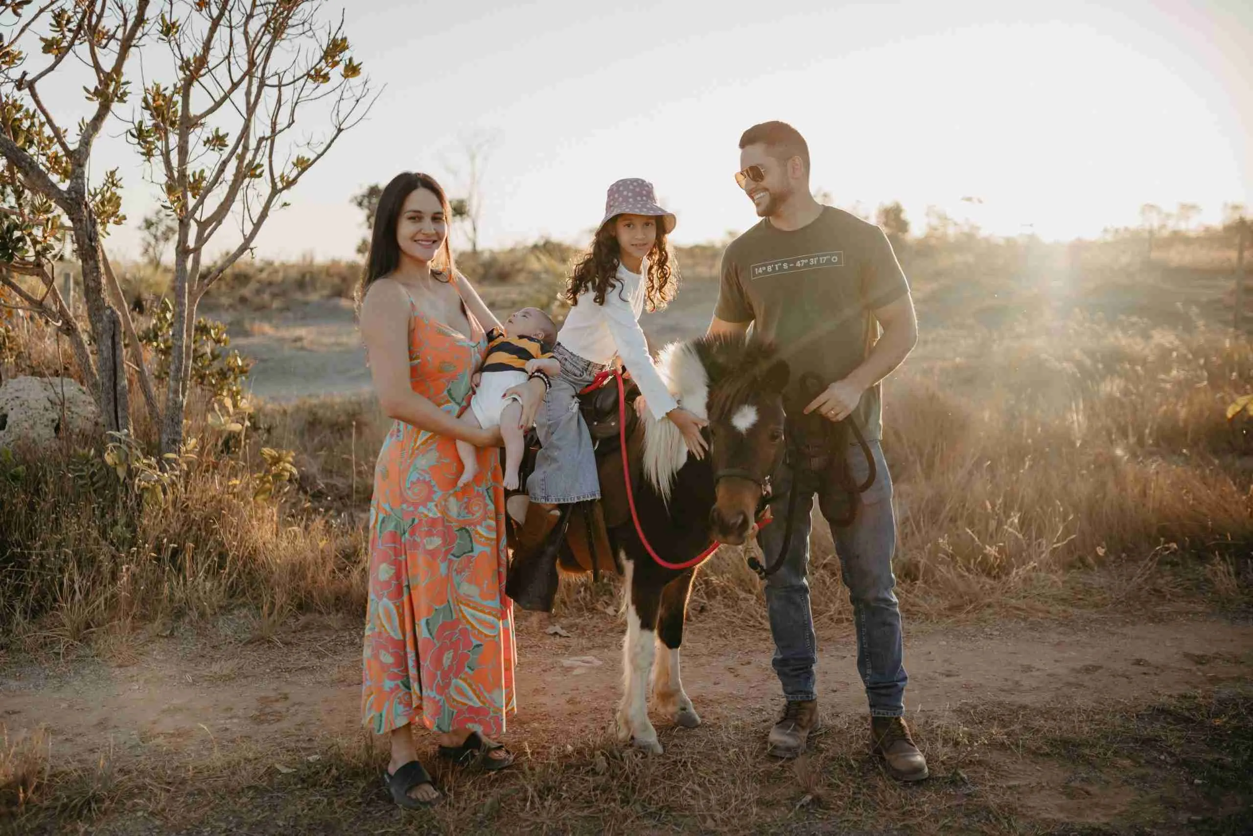 Família com bebê e filha montada em pônei posando na hora dourada no Paradise Ranch